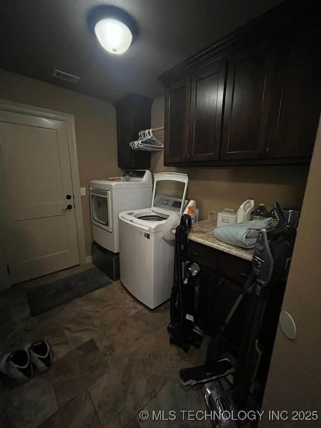 clothes washing area with washing machine and dryer, cabinet space, and visible vents
