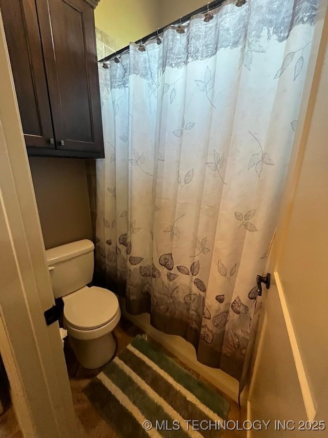 full bath featuring toilet and a shower with curtain