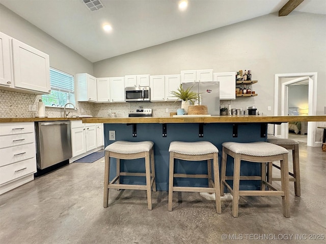 kitchen with finished concrete flooring, backsplash, stainless steel appliances, and visible vents