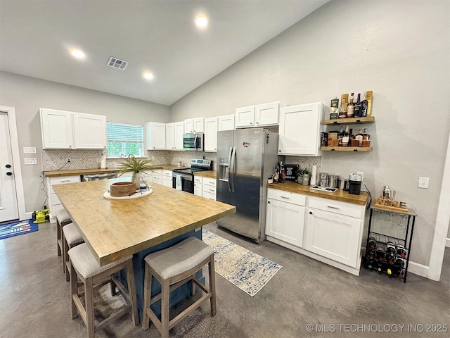kitchen with appliances with stainless steel finishes, tasteful backsplash, and finished concrete floors