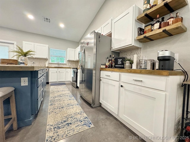 kitchen with visible vents, decorative backsplash, finished concrete flooring, and white cabinets