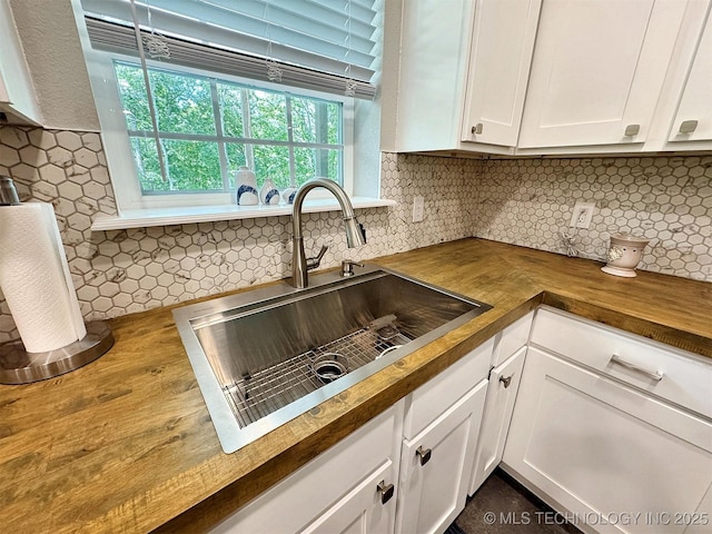 kitchen featuring white cabinetry, wooden counters, a sink, and tasteful backsplash