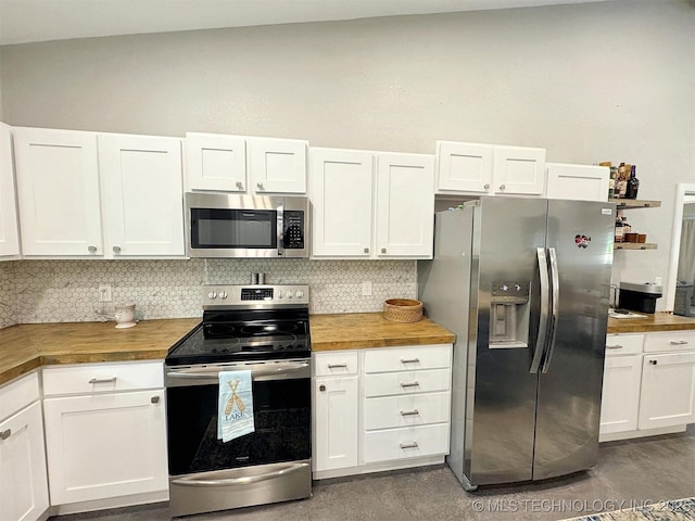 kitchen featuring white cabinets, stainless steel appliances, butcher block countertops, and decorative backsplash