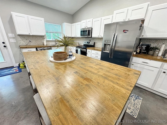 kitchen featuring wood counters, appliances with stainless steel finishes, concrete flooring, and tasteful backsplash