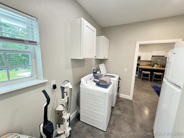 laundry area featuring cabinet space, baseboards, washer and clothes dryer, and a healthy amount of sunlight