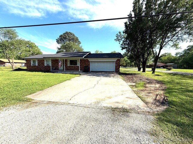 101 E Corporation St, Henryetta, OK 74437 - ranch-style house featuring concrete driveway, brick siding, covered porch, and a garage