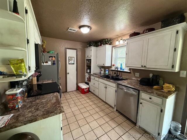 101 E Corporation St, Henryetta, OK 74437 - kitchen featuring a textured ceiling, appliances with stainless steel finishes, dark countertops, a sink, and white cabinets
