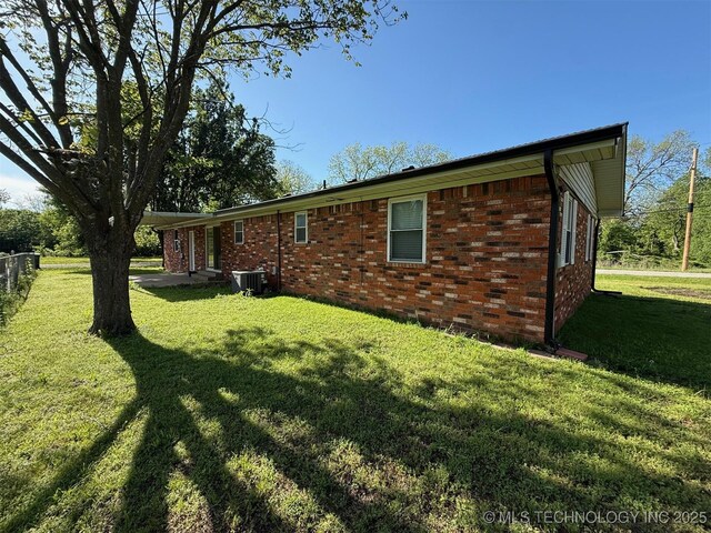 101 E Corporation St, Henryetta, OK 74437 - rear view of house with a lawn, brick siding, fence, and central air condition unit