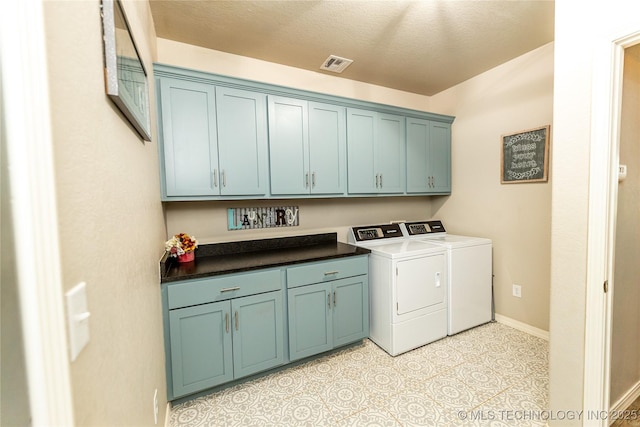 clothes washing area featuring visible vents, washer and clothes dryer, cabinet space, and baseboards