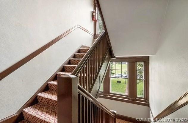 stairs with baseboards and a high ceiling