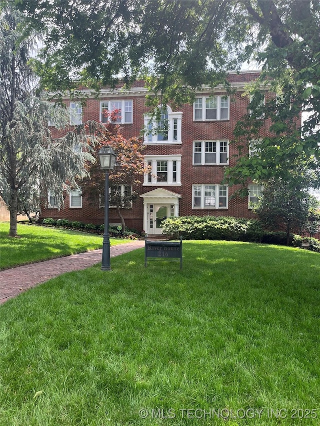 townhome / multi-family property with brick siding and a front lawn