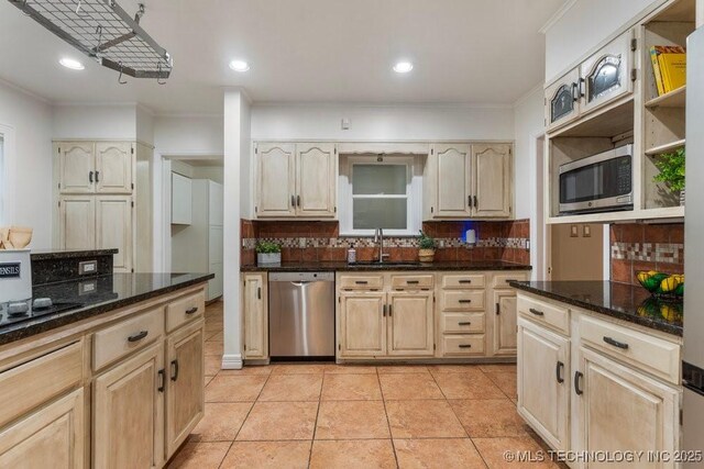 kitchen with a sink, appliances with stainless steel finishes, tasteful backsplash, and ornamental molding