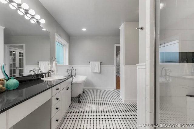 bathroom with vanity, wainscoting, tiled shower, recessed lighting, and a freestanding bath