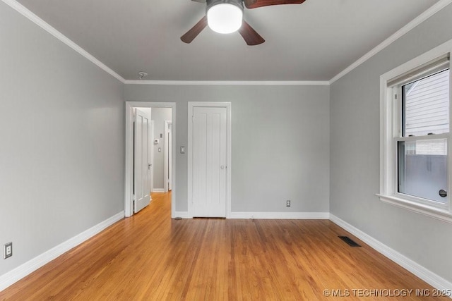 spare room with crown molding, baseboards, visible vents, and light wood finished floors