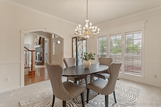 13303 E 95th Pl N, Owasso, OK 74055 - dining area featuring light colored carpet, crown molding, arched walkways, baseboards, and a chandelier