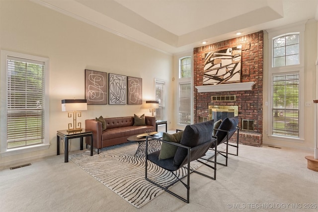 13303 E 95th Pl N, Owasso, OK 74055 - carpeted living room with visible vents, a raised ceiling, a brick fireplace, and a towering ceiling