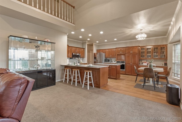 13303 E 95th Pl N, Owasso, OK 74055 - kitchen with crown molding, a peninsula, appliances with stainless steel finishes, and brown cabinets