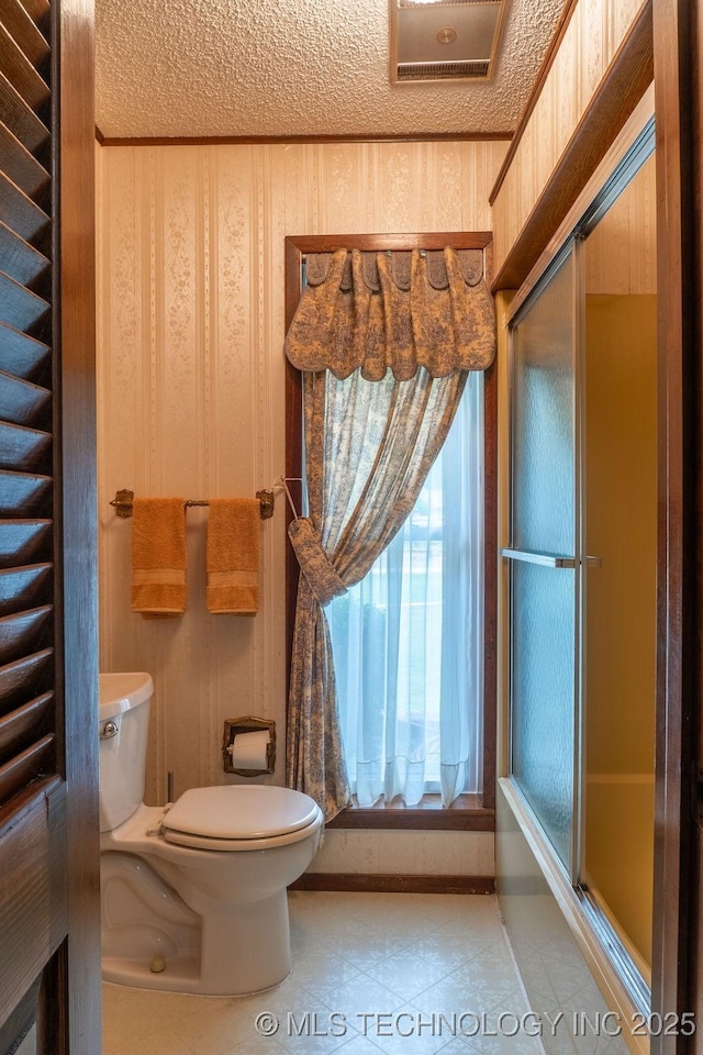 bathroom featuring toilet, a textured ceiling, baseboards, and tile patterned flooring