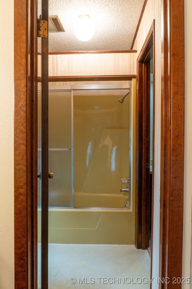 bathroom with a textured ceiling, visible vents, and tub / shower combination