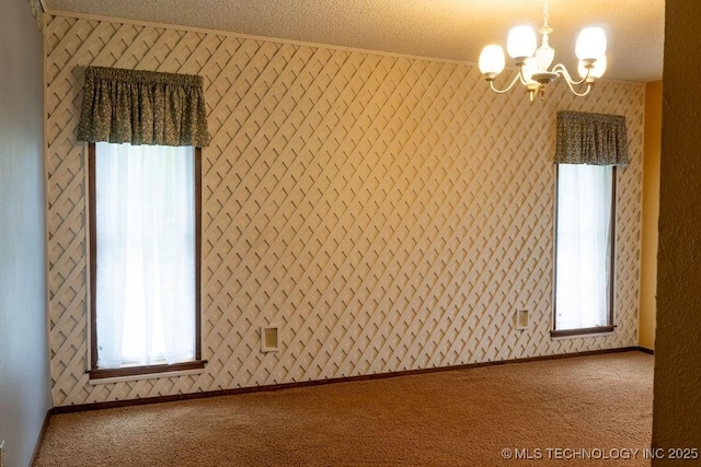 carpeted empty room with crown molding, a textured ceiling, and an inviting chandelier