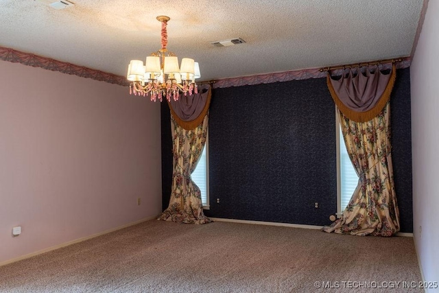 carpeted empty room featuring a textured ceiling, visible vents, and an inviting chandelier