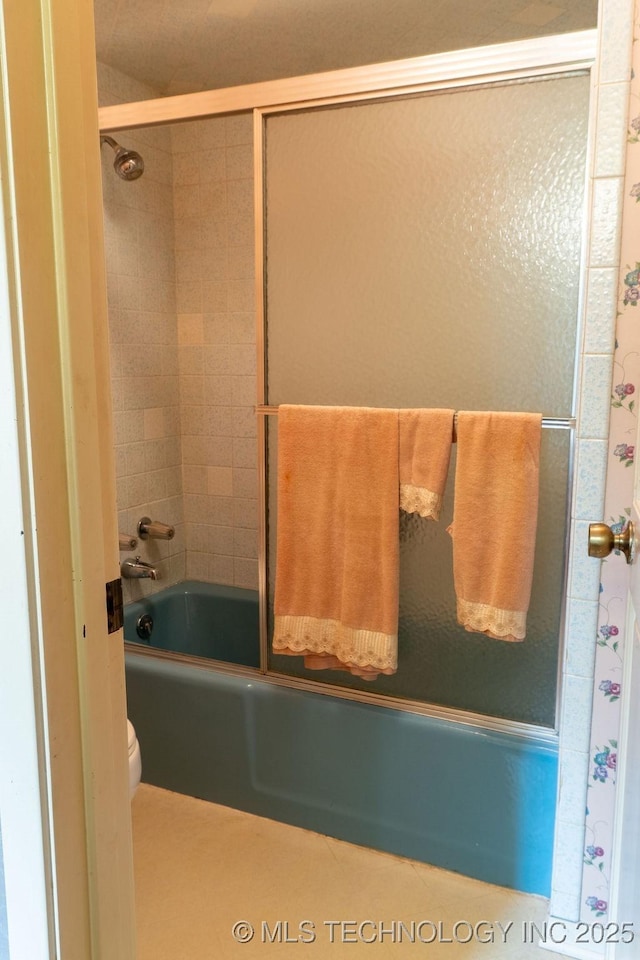 bathroom featuring enclosed tub / shower combo and toilet