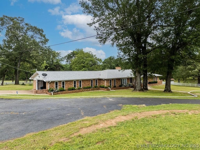 ranch-style home with a chimney, driveway, a front lawn, and brick siding