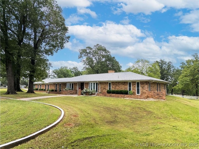 view of front facade featuring a chimney, a front yard, driveway, and brick siding