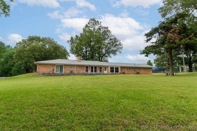 rear view of house with a lawn and brick siding