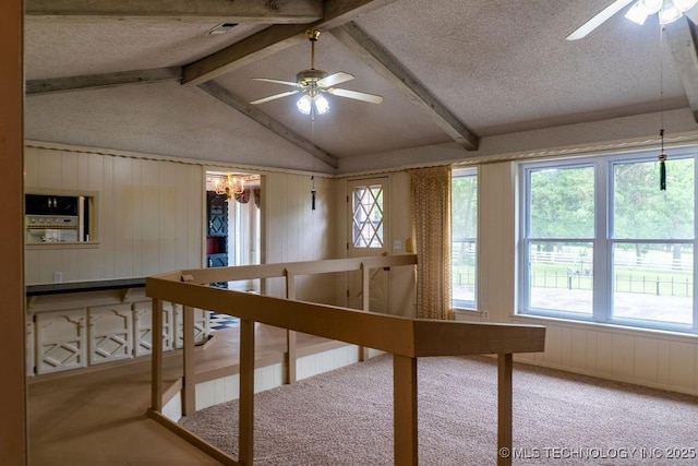 interior space featuring carpet floors, plenty of natural light, and ceiling fan with notable chandelier