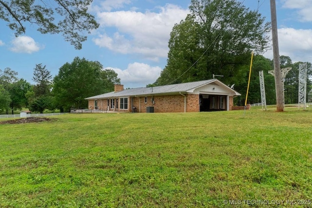 rear view of property featuring a lawn, a chimney, and brick siding