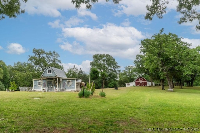 view of yard featuring a barn, an outdoor structure, and a porch