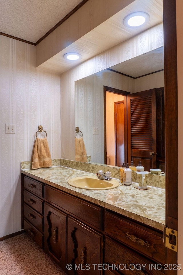 bathroom with crown molding, vanity, wallpapered walls, and a textured ceiling