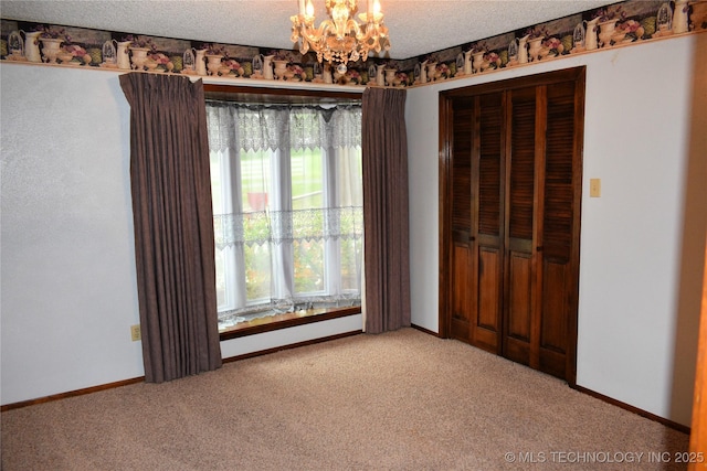 unfurnished bedroom with a closet, light colored carpet, a textured ceiling, and a notable chandelier