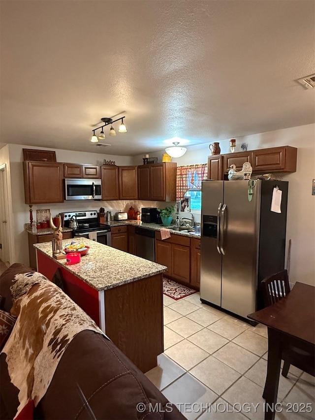 kitchen featuring light stone countertops, appliances with stainless steel finishes, a textured ceiling, light tile patterned floors, and visible vents