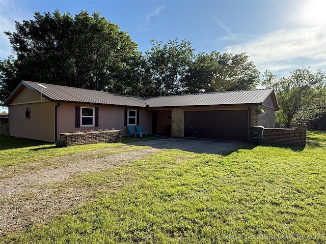 ranch-style home with aphalt driveway, metal roof, a garage, brick siding, and a front lawn
