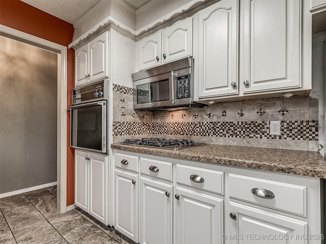 kitchen with baseboards, dark stone counters, white cabinetry, tasteful backsplash, and appliances with stainless steel finishes