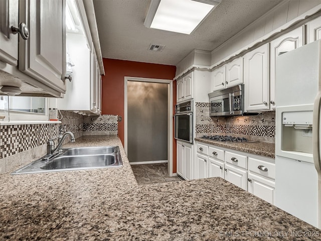 kitchen with white cabinets, appliances with stainless steel finishes, a sink, tasteful backsplash, and visible vents
