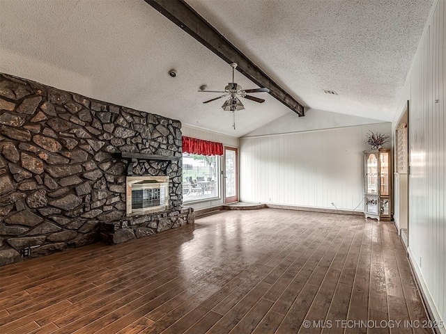 unfurnished living room with wood finished floors, a fireplace, ceiling fan, vaulted ceiling with beams, and a textured ceiling