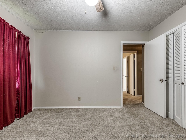 unfurnished bedroom featuring carpet floors, a textured ceiling, baseboards, and a ceiling fan