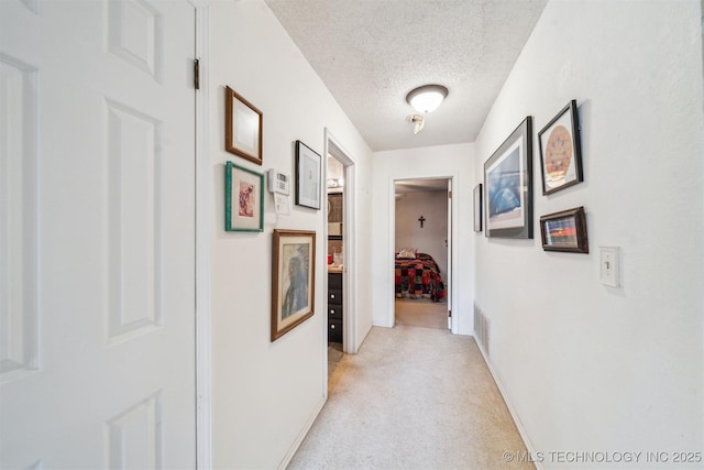 25805 S Clayton Ave, Claremore, OK 74019 - hall featuring a textured ceiling, visible vents, light carpet, and baseboards