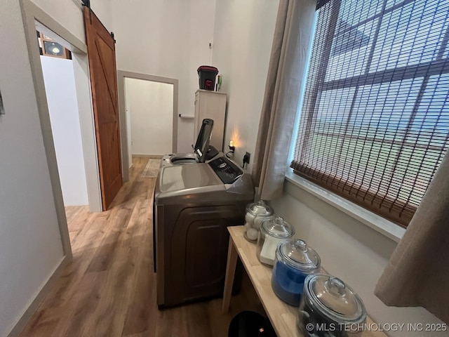 washroom with independent washer and dryer, laundry area, a barn door, and light wood finished floors