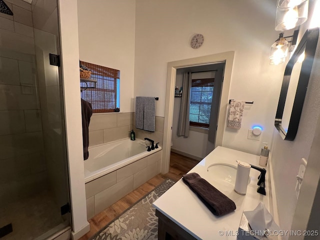 full bath featuring a bath, vanity, a stall shower, and wood finished floors