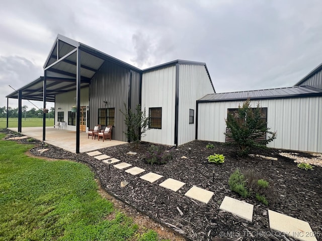 rear view of property featuring a patio, a pole building, and a yard