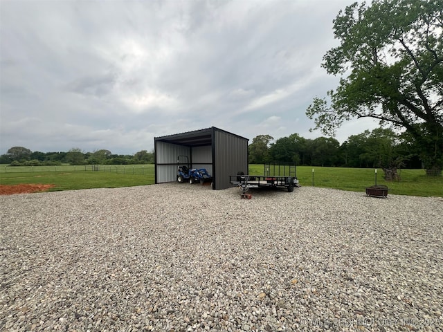 view of pole building with a yard, a rural view, fence, and a detached carport