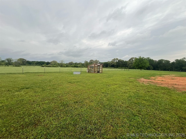 view of yard with an outdoor structure, fence, and a rural view