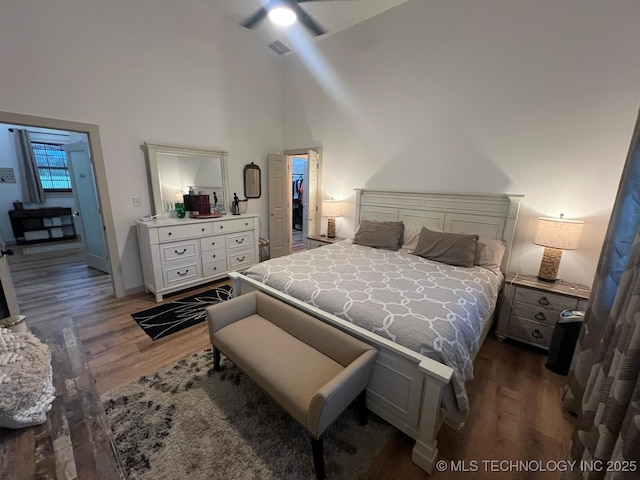 bedroom with ceiling fan, high vaulted ceiling, baseboards, wood finished floors, and visible vents