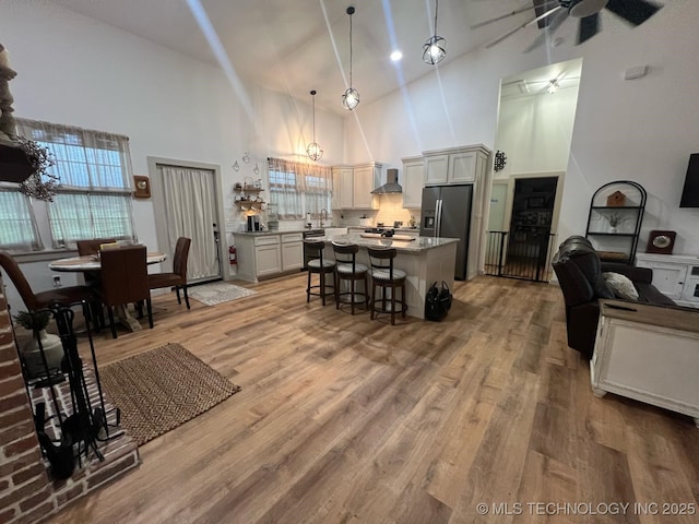 interior space with a ceiling fan, high vaulted ceiling, and light wood-style floors
