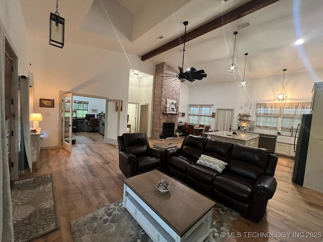 living room featuring beam ceiling, light wood-style floors, high vaulted ceiling, baseboards, and visible vents