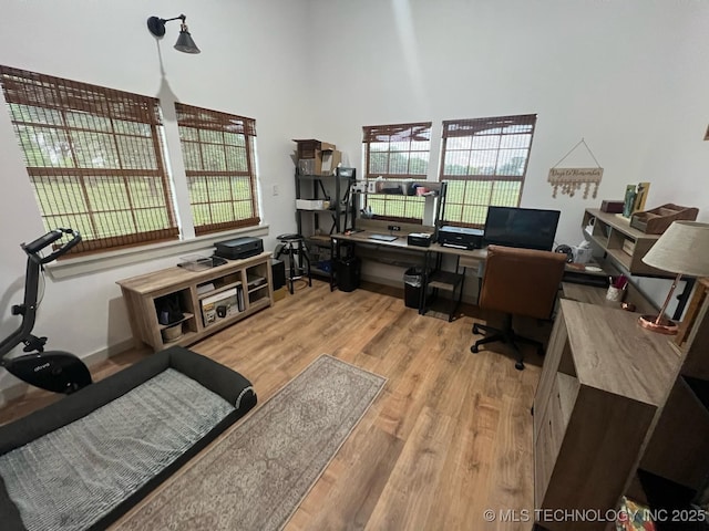 office space featuring a healthy amount of sunlight, wood finished floors, and a towering ceiling